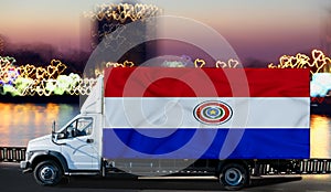Paraguai flag on the side of a white van against the backdrop of a blurred city and river. Logistics concept photo