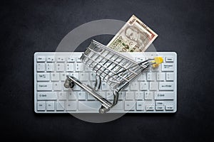 Paraguay banknote, White computer keyboard, Miniature shopping cart, Black background, Online shopping concept in stores, Low