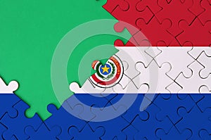 Paraguay flag is depicted on a completed jigsaw puzzle with free green copy space on the left side