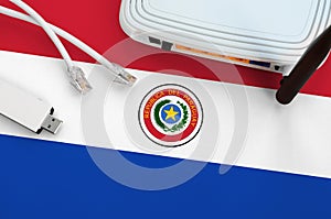 Paraguay flag depicted on table with internet rj45 cable, wireless usb wifi adapter and router. Internet connection concept
