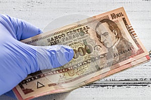 Paraguayan money, Guaranies banknotes kept in rubber gloves. The concept of economy and financial threats during the Coronavirus photo