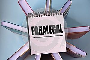 PARALEGAL - word on a yellow piece of paper on the background of books