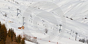 Parallel, long ski chair lift cable lines in Les Sybelles, France, on a sunny bright day with perfect skiing weather.