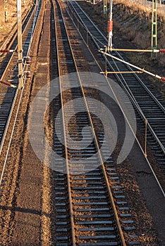 Parallel railway tracks and power lines in low sunlight.