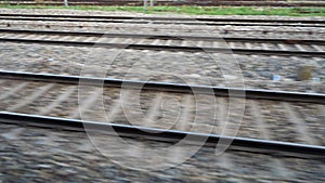 Parallel tracks running along a speeding Train with trees and electric poles leaving behind. Northern Indian Railways. India