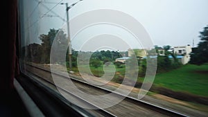 Parallel tracks running along a speeding Train with trees and electric poles leaving behind. Northern Indian Railways. India