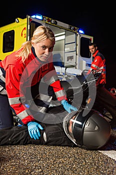 Paramedic assisting motorbike driver at night