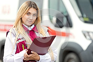 Paramedic with clipboard at emergency car background