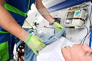 Paramedic covers a patient with a soft blanket in ambulance