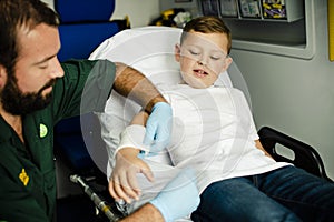 Paramedic giving a first aid to a young boy in an ambulance