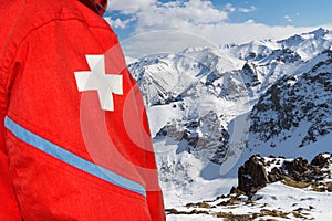 Paramedic on mountain slope in red clothes with white cross