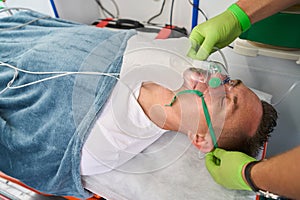 Paramedic puts oxygen mask on patient in ambulance