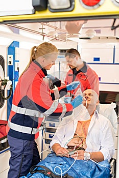 Paramedic putting oxygen mask on patient ambulance