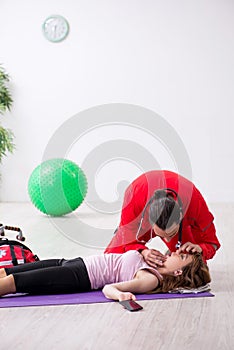 Paramedic in red visiting young woman in gym