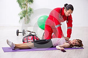 Paramedic in red visiting young woman in gym