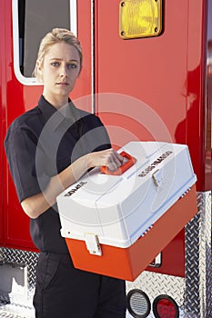 Paramedic standing by ambulance with medical kit