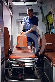 Paramedic standing with his medical bag in an ambulance car