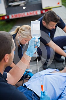 Paramedic team preparing drip for injured patient