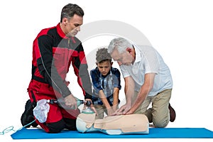 Paramedic training cardiopulmonary resuscitation to senior man and boy