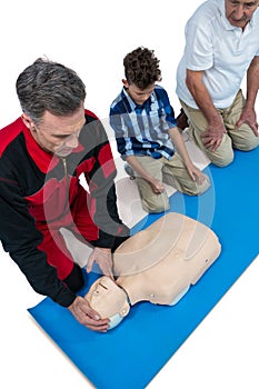 Paramedic training cardiopulmonary resuscitation to senior man and boy