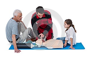 Paramedic training cardiopulmonary resuscitation to senior man and girl