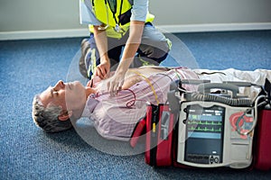 Paramedic using an external defibrillator on an unconscious patient