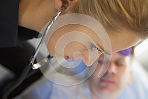 Paramedic using stethoscope on patient