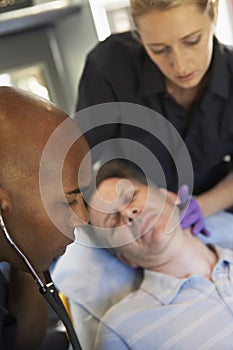 Paramedic using stethoscope on patient