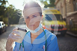 Paramedic woman with  medical mask and cup of coffee