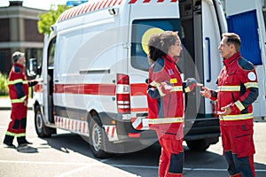 Paramedical personnel standing near the EMS vehicle during the conversation