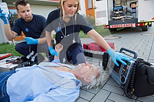 Paramedics checking pulse of unconscious man photo