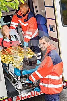 Paramedics helping woman on stretcher in ambulance photo