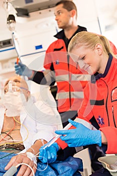 Paramedics injecting sick patient in ambulance aid photo