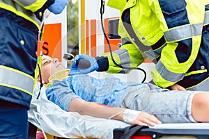 Paramedics measuring blood pressure of injured boy