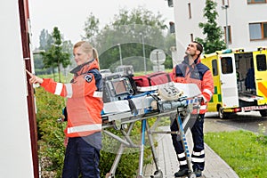 Paramedics with medical equipment ringing doorbell photo