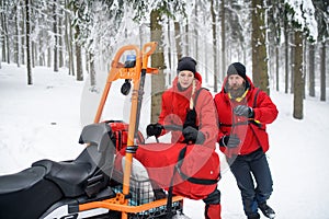 Paramedics from mountain rescue service provide operation outdoors in winter in forest.