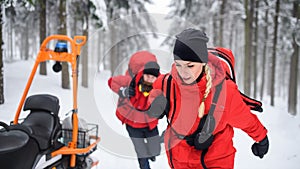 Paramedics from mountain rescue service provide operation outdoors in winter in forest.