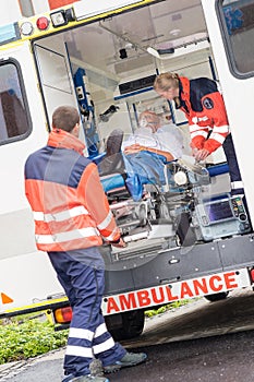 Paramedics putting patient in ambulance car aid photo