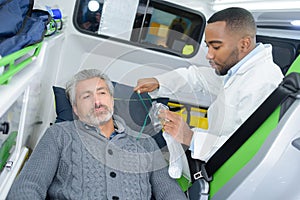 paramedics putting patient man oxygen mask in ambulance car