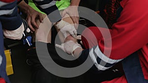 Paramedics urgently examining patient legs and knees, suspicion of bones injury