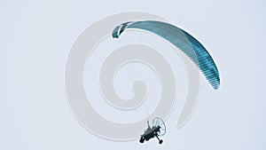 Paramotor with blue parachute flying in air