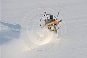 Paramotor close-up hovering above the ground and leaving a trail in the snow