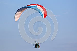 Paramotor pilot flying in a blue sky