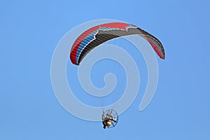 Paramotor pilot flying in a blue sky