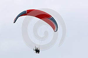 Paramotor pilot flying in a blue sky