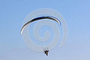 Paramotor pilot flying in a blue sky