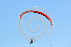 Paramotor pilot flying in a blue sky