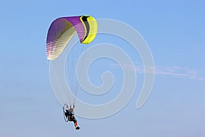 Paramotor pilot flying in a blue sky