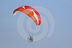 Paramotor pilot flying in a blue sky
