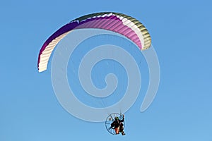 Paramotor pilot flying in a blue sky